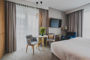 华沙Royal Tulip Warsaw Apartments的酒店客房带一张床、一张桌子和椅子