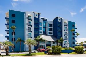 新士麦那海滩Coconut Palms Beach Resort II a Ramada by Wyndham的一座蓝色的公寓楼,停车场内种植了棕榈树