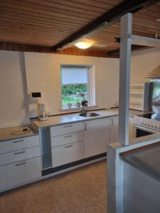 旺代尔A cozy house to stay的厨房配有白色橱柜、水槽和窗户。