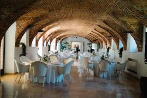 SandiglianoRELAIS CASCINA ERA的一间设有桌椅的用餐室和拱门天花板