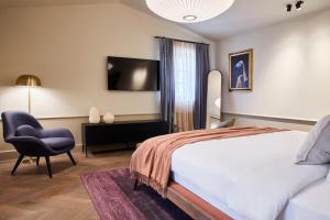 波雷奇Martis Forum Heritage Hotel & Residence的一间卧室配有一张床、一把椅子和电视