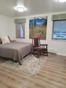 Delta JunctionAlaska Country Inn的一间卧室配有一张床、一把椅子和一幅画