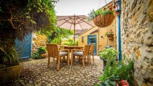 谢伯恩The Sherborne Cottage的庭院内桌椅和遮阳伞