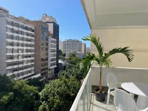 里约热内卢Precioso apartamento con terraza y piscina的阳台配有白色椅子和棕榈树