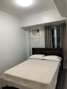 马尼拉Cozy 1 Bedroom near Alabang Town Center and Molito with Wifi and Netflix的一间卧室配有一张带白色毯子的大床