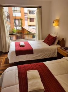 库斯科Eco Bunnu Inn的酒店客房设有两张床和窗户。