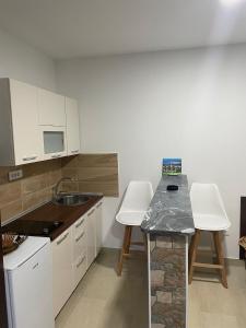 维舍格勒Apartman Sara的厨房配有白色橱柜和带水槽的台面