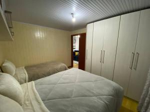 卡内拉Casa em meio a Natureza.的一间卧室设有两张床和白色橱柜。