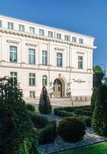 弗罗茨瓦夫Hotel Altus Palace的一座白色的大建筑,前面有一个花园