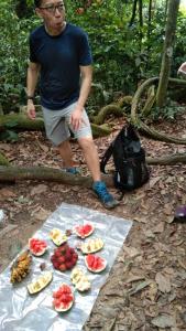 武吉拉旺Bukit Lawang Glamping & Jungle Trekking的站在桌子旁,一边拿着水果