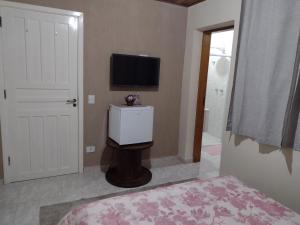 坎波斯杜若尔当Casa do Trem Suítes的卧室配有壁挂式平面电视。