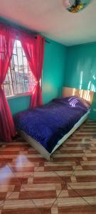 圣地亚哥Casa Enea Pudahuel的一间卧室配有一张带紫色床单和红色窗帘的床