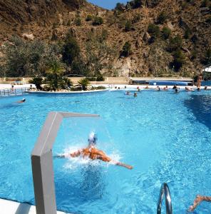 阿尔切纳巴尔尼尔里奥阿尔切纳莱昂酒店的在山中游泳池游泳的人