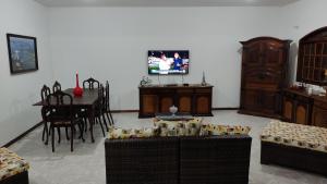 里约达欧特拉斯Praia Virgem Hostel的客厅配有椅子、桌子和电视