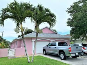 卡纳维拉尔角Cape Canaveral near Beach House的一辆卡车停在一个两棵棕榈树的粉红色房子前面
