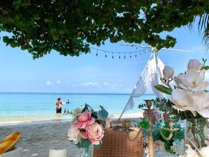 沙美岛Kerala Coco Resort的海滩上的桌子,上面有鲜花和水里的人