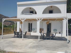 克拉托坎波斯Mini Villas Avra的白色的房子,配有桌子和椅子