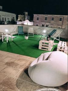 滨海波利尼亚诺B&B VOLARE的一间设有绿色地板的客房,屋顶上配有椅子