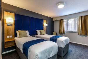 沃里克戴斯沃里克北界M40酒店的两张位于酒店客房的床,拥有蓝色的墙壁