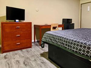 萨克拉门托Rodeway Inn Sacramento-University Area的一间卧室配有一张床和一个带电视的梳妆台