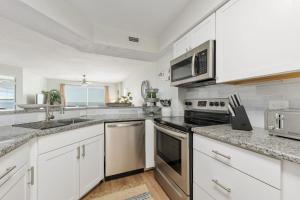 奥蒙德海滩Sea Winds 501 - Corner Breeze的厨房配有白色橱柜和不锈钢用具