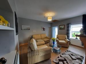 克利夫登Conneelys Cottage, Connemara, Clifden, H71Y096的客厅配有沙发和两把椅子