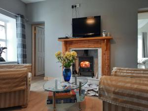 克利夫登Conneelys Cottage, Connemara, Clifden, H71Y096的客厅设有壁炉,楼上配有电视