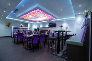 阿尔梅勒Hotel Cataleya的餐厅设有紫色桌椅和大型天花板