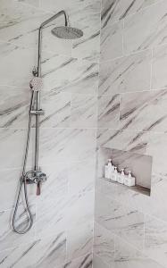 哈德姚Mayara pool villas的浴室铺有白色大理石瓷砖,设有淋浴。