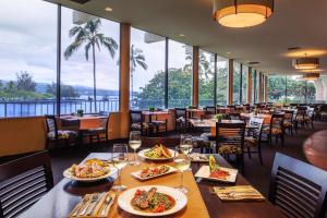 希洛Castle Hilo Hawaiian Hotel的餐桌上放有盘子的餐厅