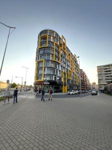 布拉格VIT Apartment - Free Parking - O2 Arena的一座高大的黄色建筑,前面的人在步行