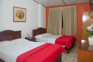皮乌拉圣何塞酒店的两张位于酒店客房的床,配有红色和白色床单