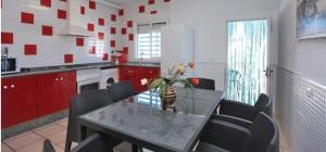 加的斯Casa Enrique的厨房配有玻璃桌、椅子和红色橱柜
