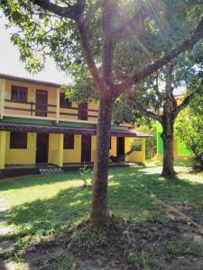 韦尔卡鲍Pousada Abacateiro的一座黄色的建筑,在院子里有两棵树