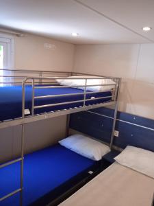 阿梅利亚Mobile home Comfort Ameglia - including airco - Camping River- 327的客房设有2张双层床,配有蓝色床单