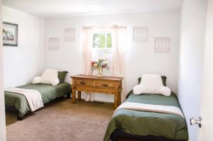 奥勒姆Cozy Cottage Retreat in the Heart of Utah Valley的客房设有两张床和一张带窗户的桌子。