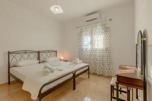 Agios Georgios ThalassitiHouse on the black beach with sea view and parking的一间卧室配有一张带白色床单的床和一扇窗户。