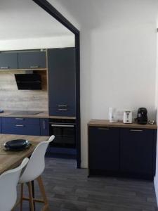 卡尔卡松Spacieux appartement au pied de la cité médiévale的厨房配有蓝色橱柜和桌椅