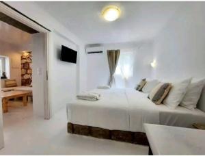 阿波罗尼亚Villa DORIANA IN PELEKOUDA的一间白色的卧室,配有床和客厅