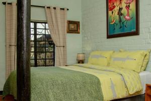 霍维克The Green Lantern - Howick的一间卧室配有一张带黄色床单的床和一扇窗户。