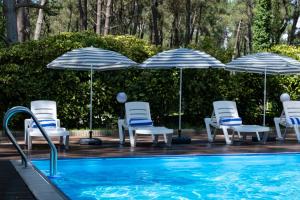 谢赫维蒂利Buxus Hotel Shekvetili的一组椅子和遮阳伞,位于游泳池旁