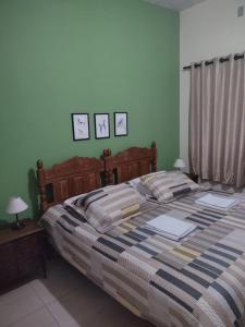 圣巴巴拉Pousada Capão da Coruja的卧室配有一张大床,墙上挂有两张照片