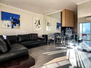 约翰内斯堡Splice Apartments的一间带黑色沙发的客厅和一间厨房