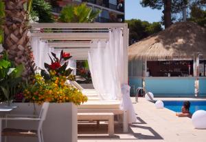 马盖鲁夫INN Mallorca Aparthotel的一座带白色天篷、椅子和鲜花的游泳池