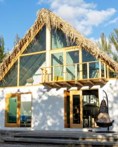 图斯潘罗德里格斯卡诺Coconi House的一个带稻草屋顶和阳台的房子