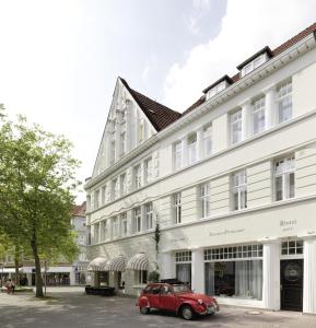 巴特萨尔茨乌夫伦小格鲁纳尔酒店及咖啡馆的停在白色建筑前的老红色汽车