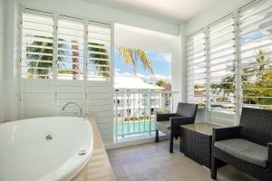 道格拉斯港Beach Club Port Douglas 3 Bedroom Penthouse的一间带浴缸和椅子的浴室以及一个阳台