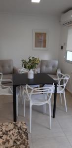 内乌肯DEPARTAMENTO AMOBLADO NEUQUEN 2的客厅配有黑桌和白色椅子