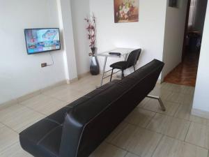 齐克拉约Departamento - Los Mitos del Parque M2的客厅配有一张黑色沙发,设有一张桌子