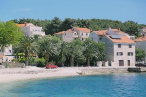 苏曼婷Apartments by the sea Sumartin, Brac - 11651的一辆红色的汽车停在房子旁边的海滩上